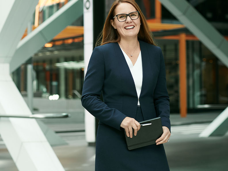 A businesswoman with glasses standing outside a Macquarie office. Macquarie - Julia