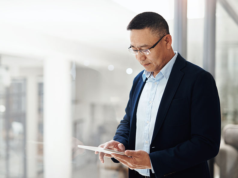 Mature asian businessman using a digital tablet in an office environment