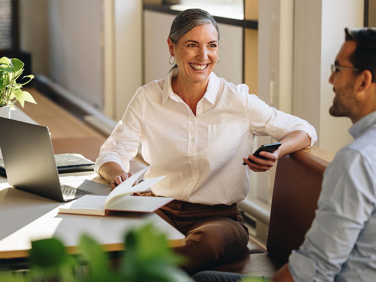 Business woman smiling with man at desk