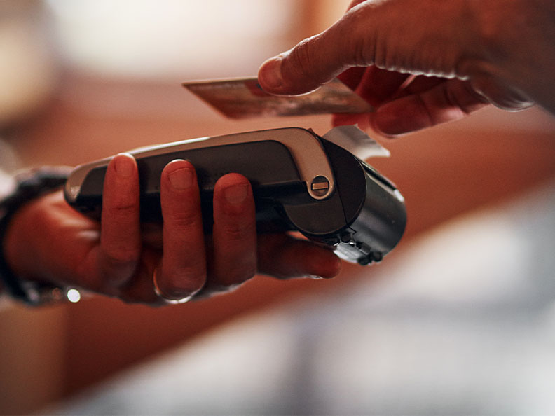 A person makes payment with a credit card as the employee holds out the payment terminal.