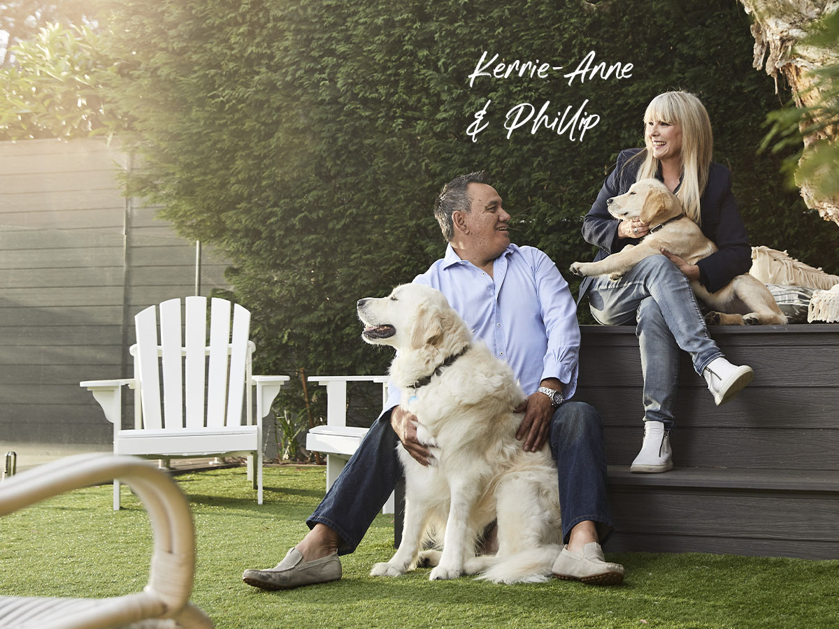 Kerrie-Anne and Phillip home loan customers smiling and sitting with two dogs in backyard