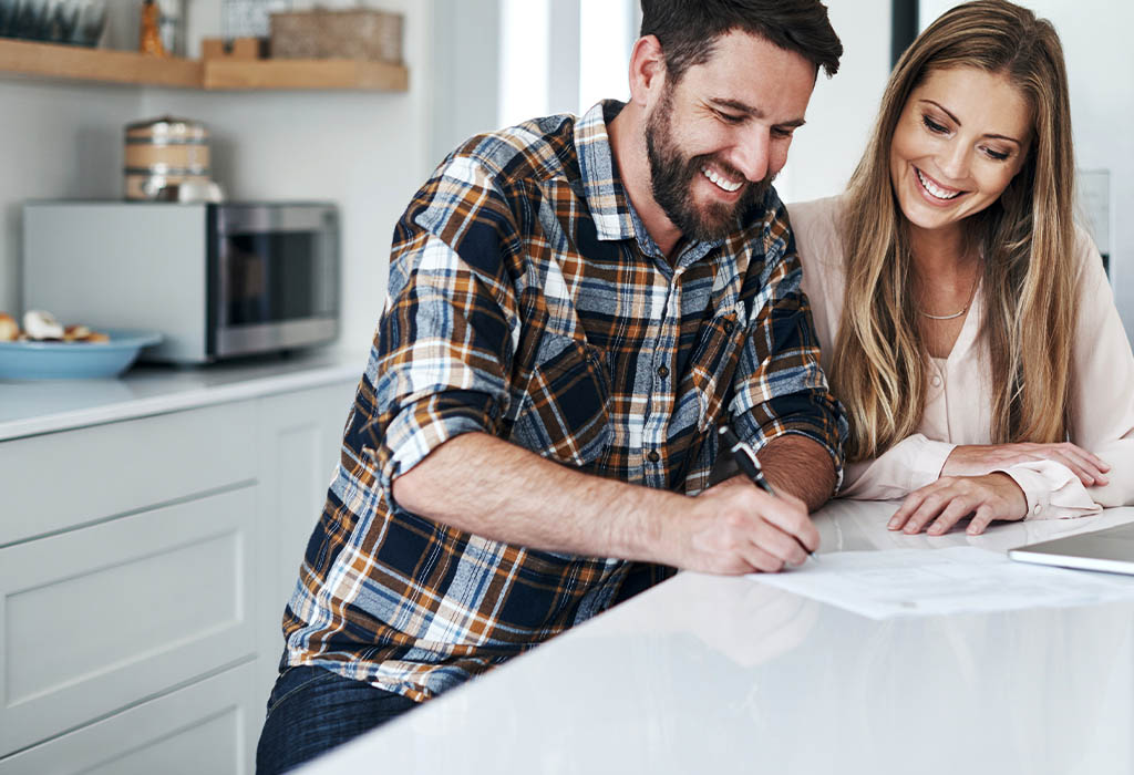 Young couple in kitchen signing home loan