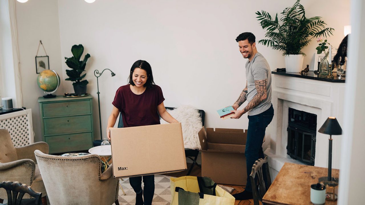 Happy couple unpacking boxes in living room at new home