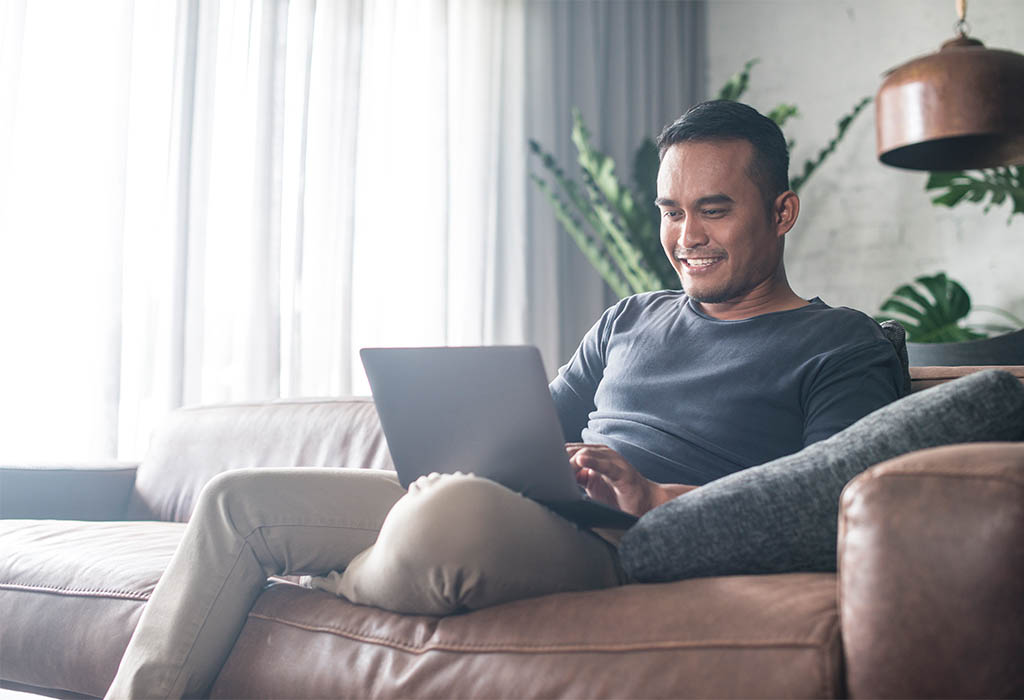 Man on lounge with laptop in casual home setting
