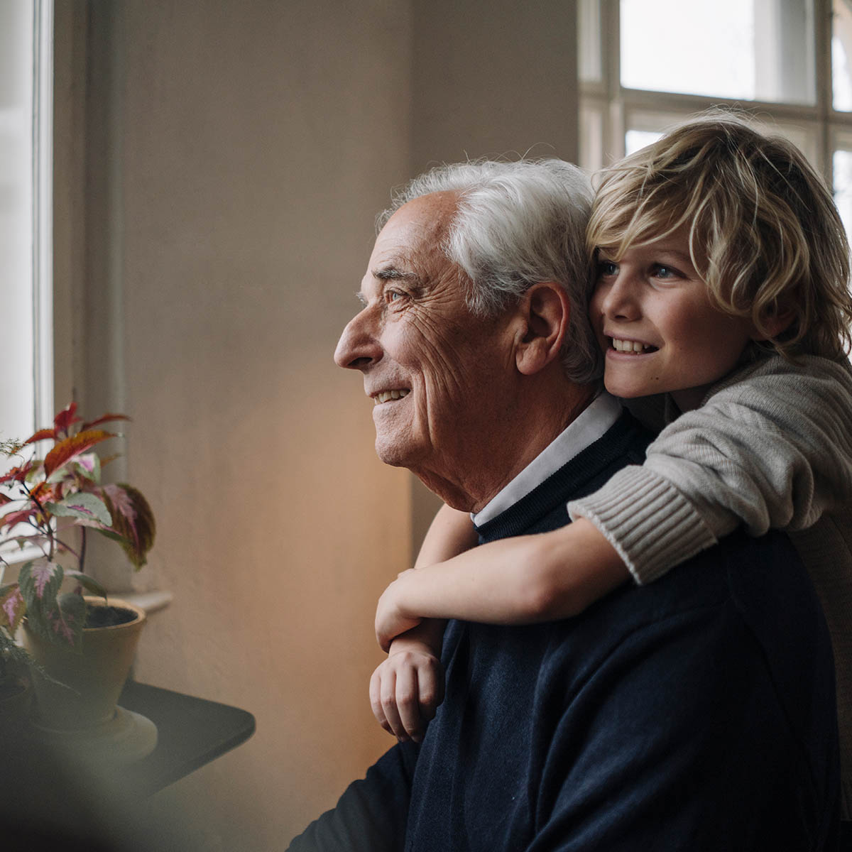 Happy grandson embracing grandfather at home